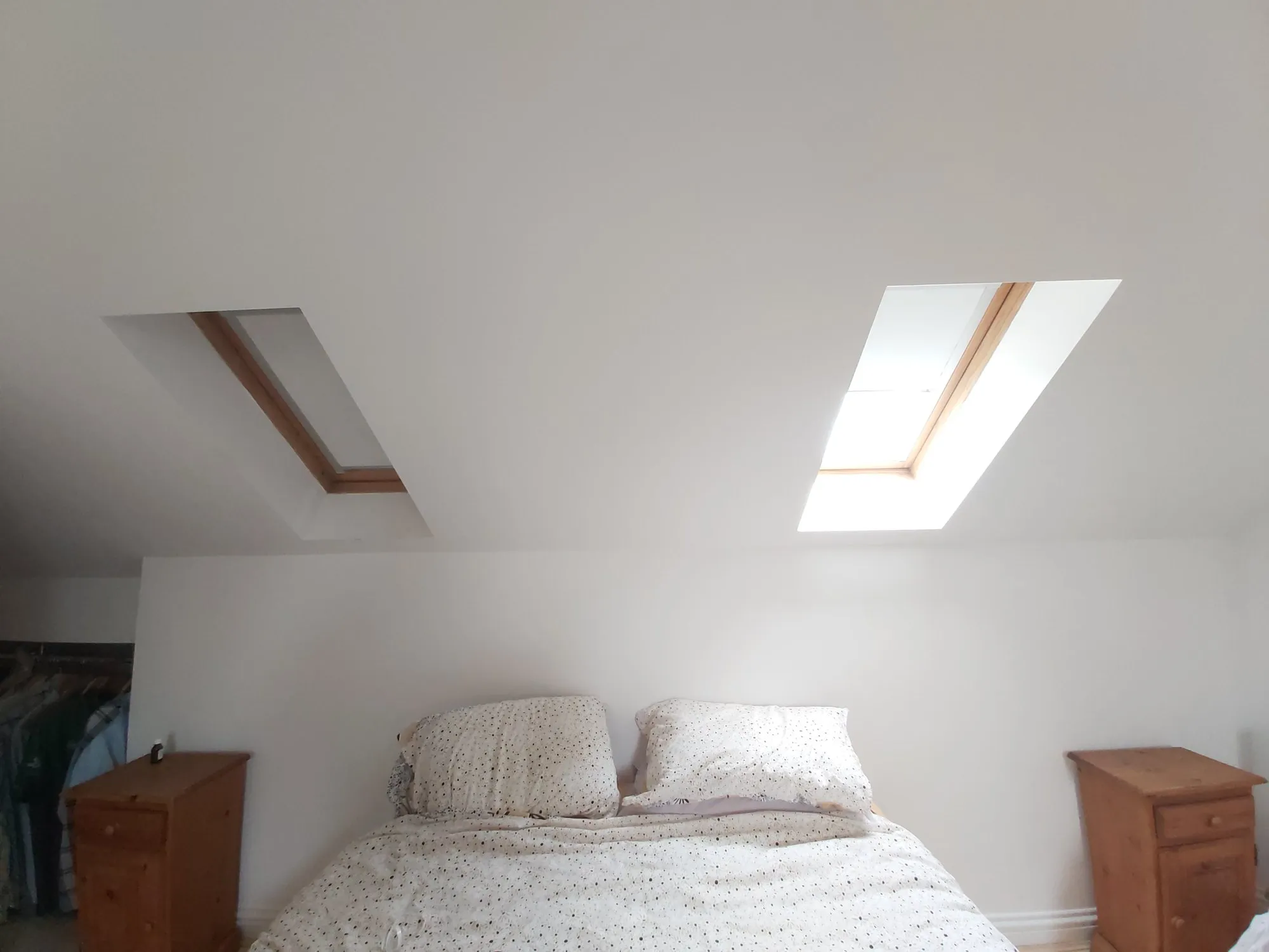 Two roof window blinds fitted in the sloping ceiling above a double bed