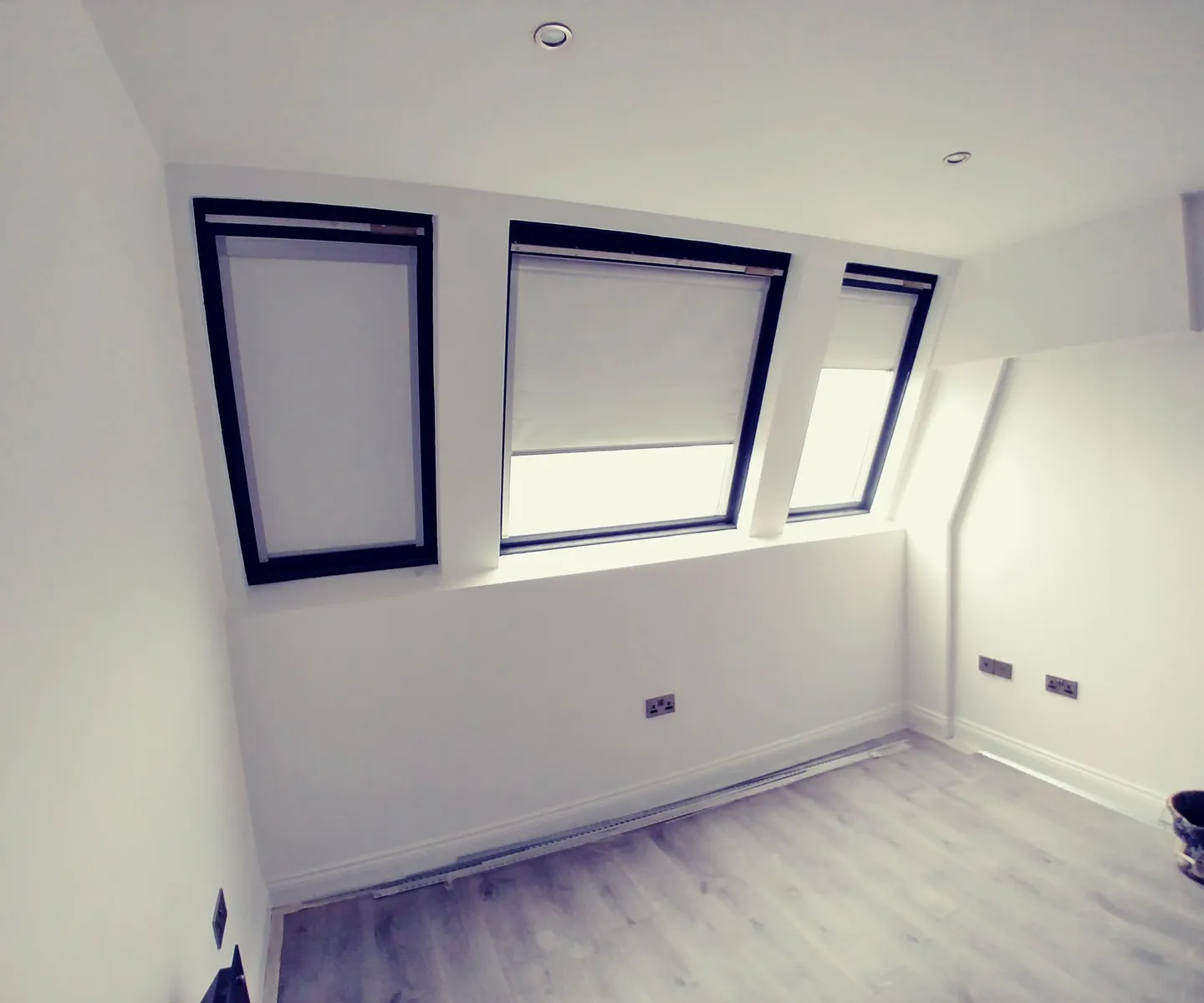Three blackout roller blinds fitted to the angled windows of a dormer loft bedroom