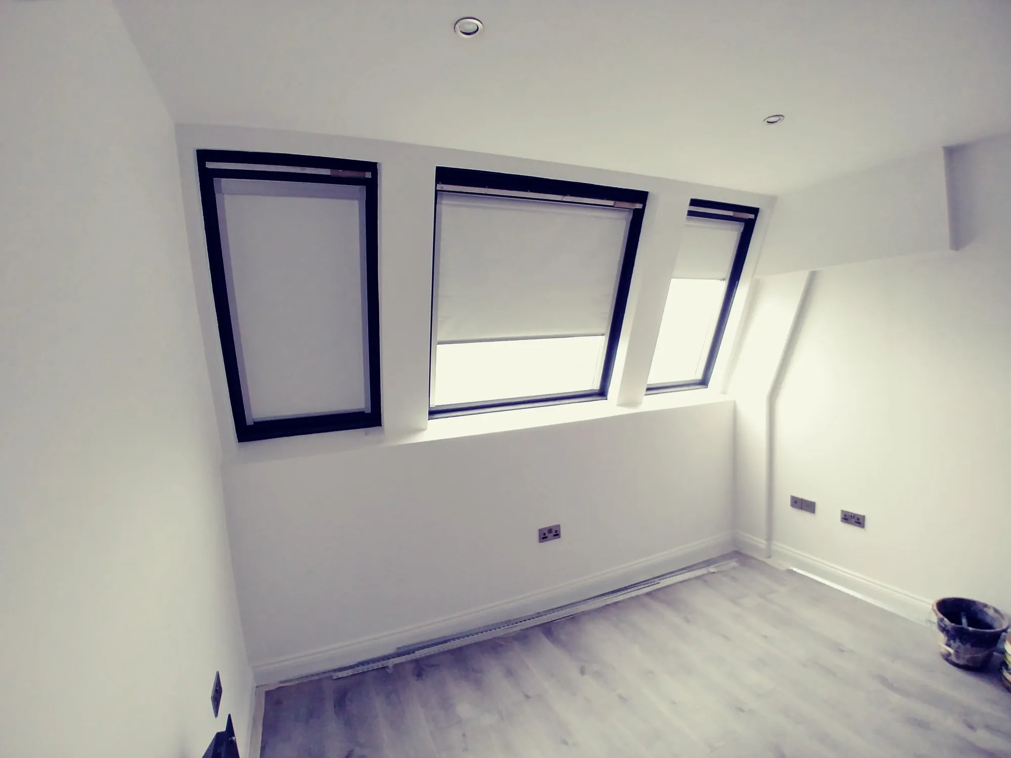 Three blackout roller blinds fitted to the angled windows of a dormer loft bedroom