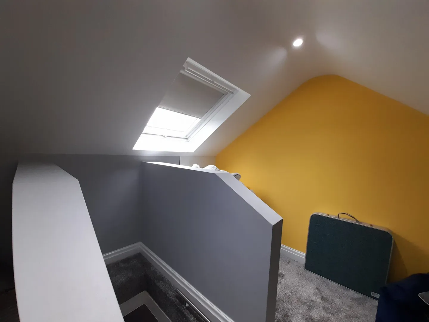 A skylight blind fitted to the pitched ceiling above a carpeted loft landing