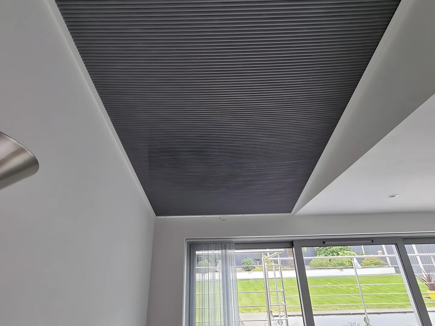 Grey pleated blind fitted across a roof lantern above a kitchen diner with garden doors