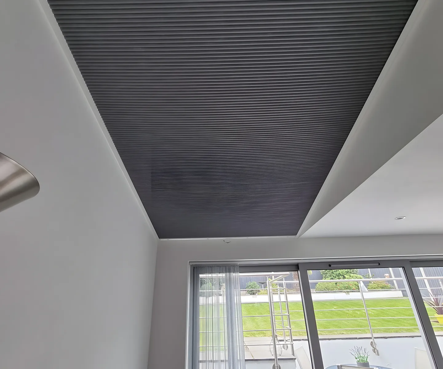 Grey pleated blind fitted across a roof lantern above a kitchen diner with garden doors