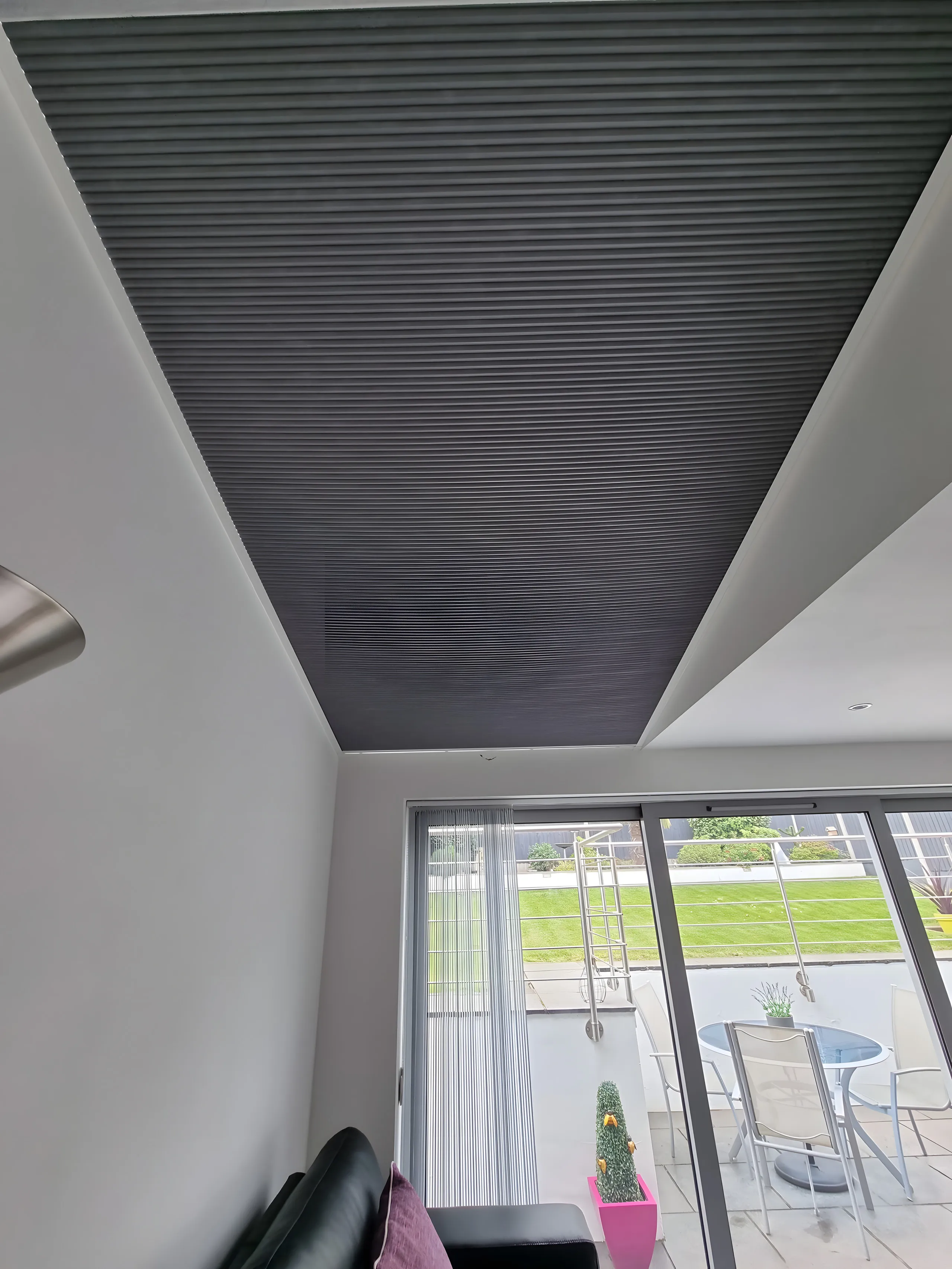Grey pleated blind fitted across a roof lantern above a kitchen diner with garden doors