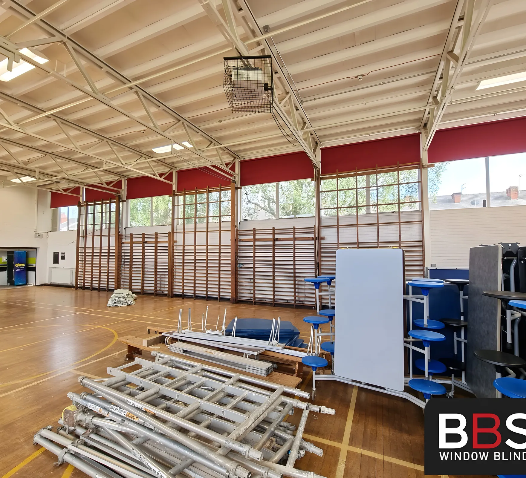 Burgundy blinds fitted high into the roof steelwork above the wall bars in the Stockport School sports hall