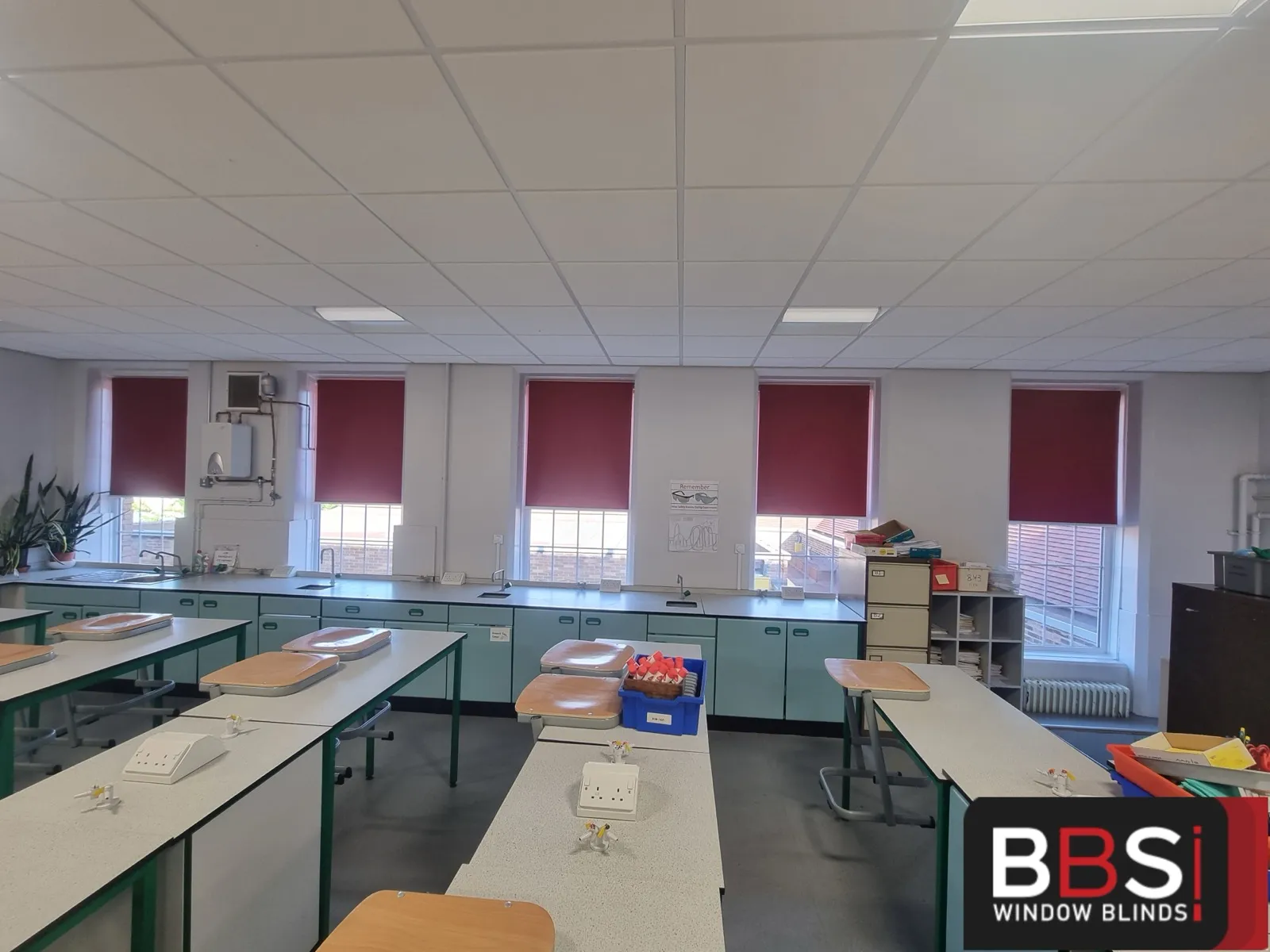 A run of burgundy roller blinds set to a matching drop along a Stockport School science lab