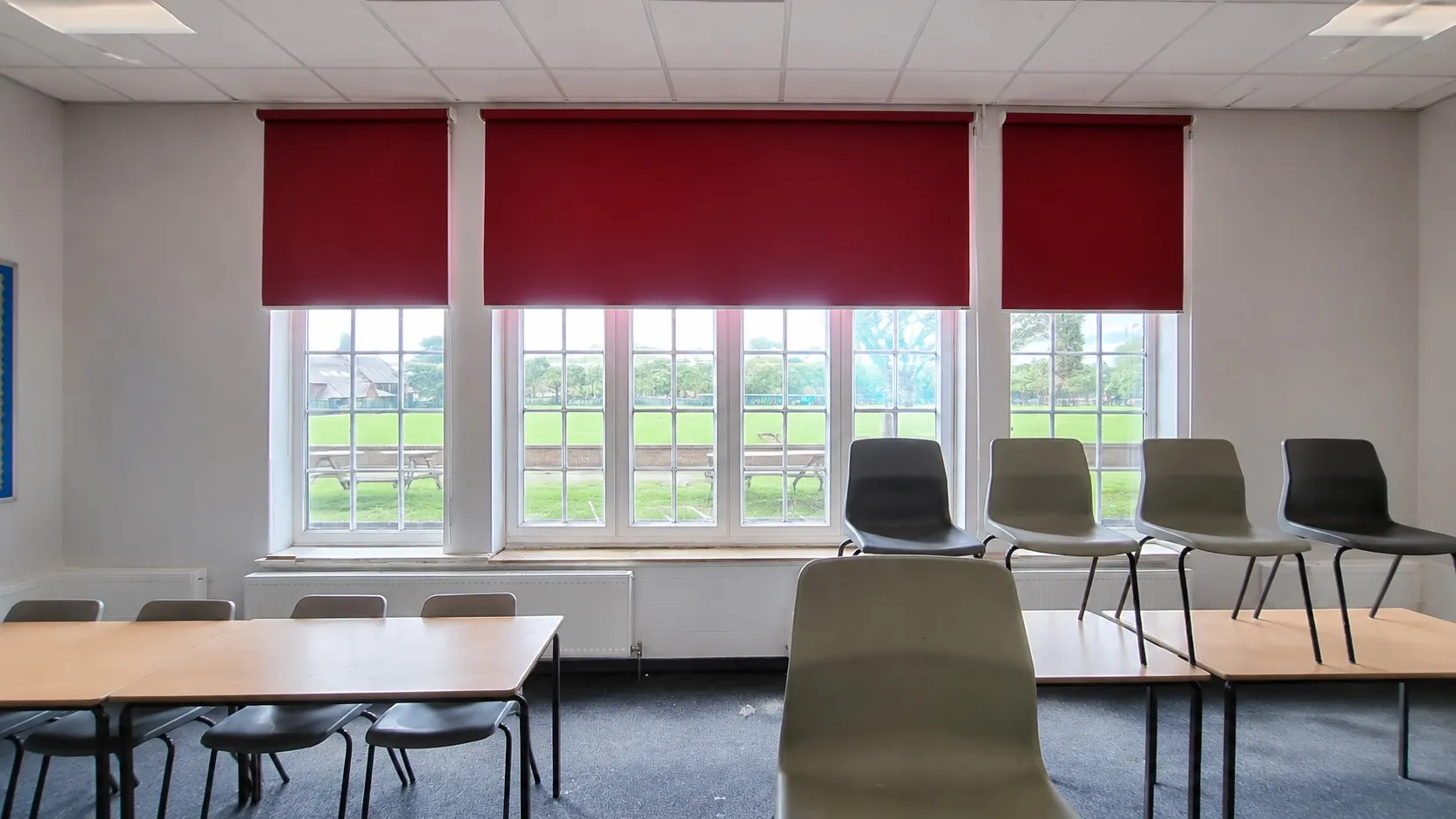 Red roller blinds fitted in a modern UK classroom