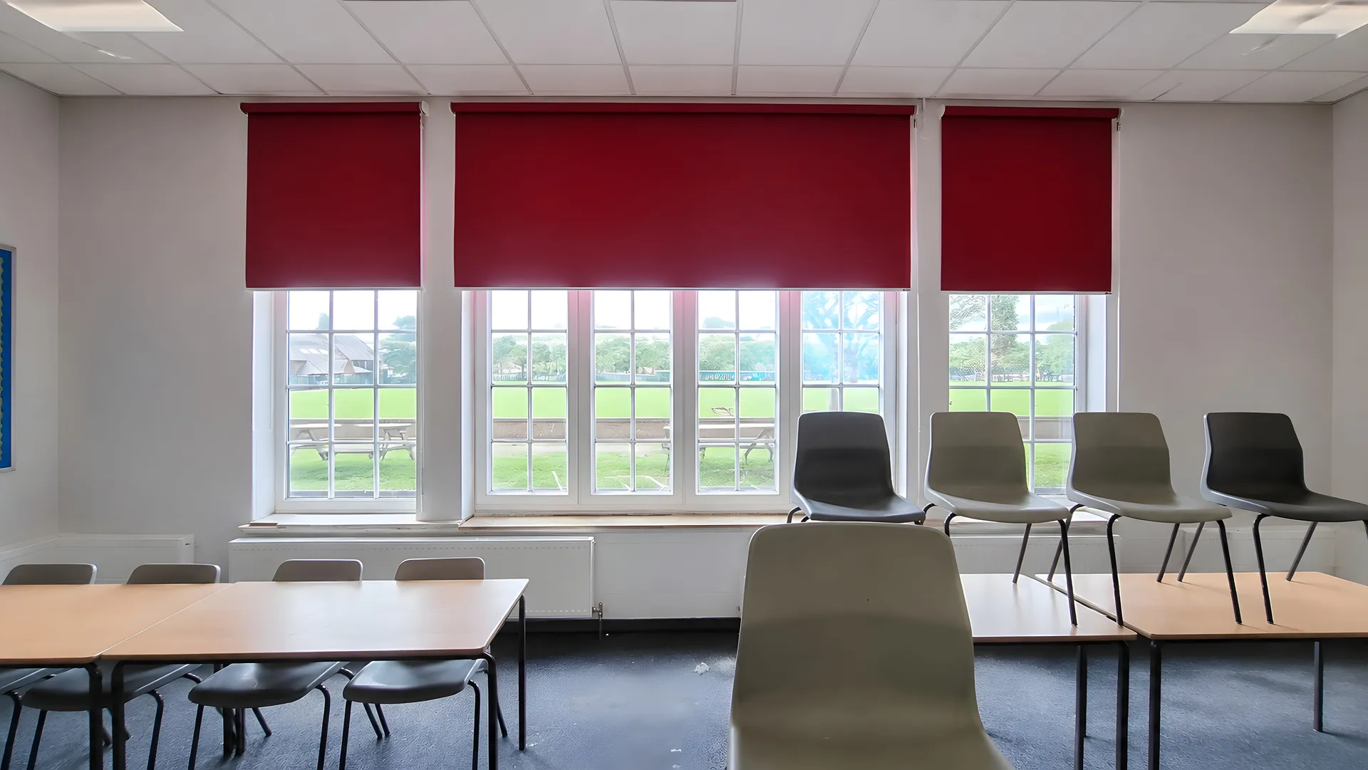 Red roller blinds controlling glare in a modern UK classroom