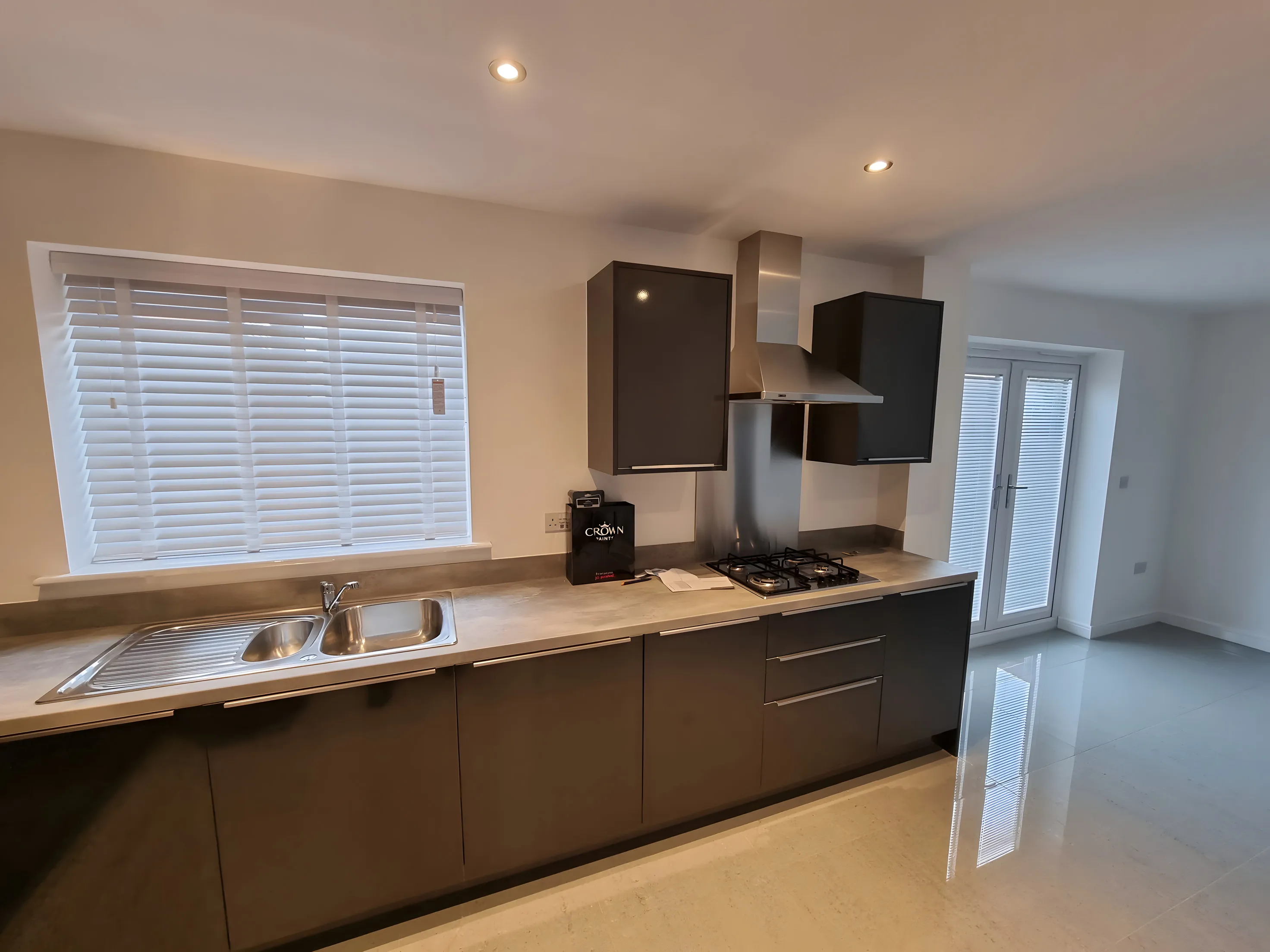 White Venetian blinds above the worktop of a grey handleless kitchen