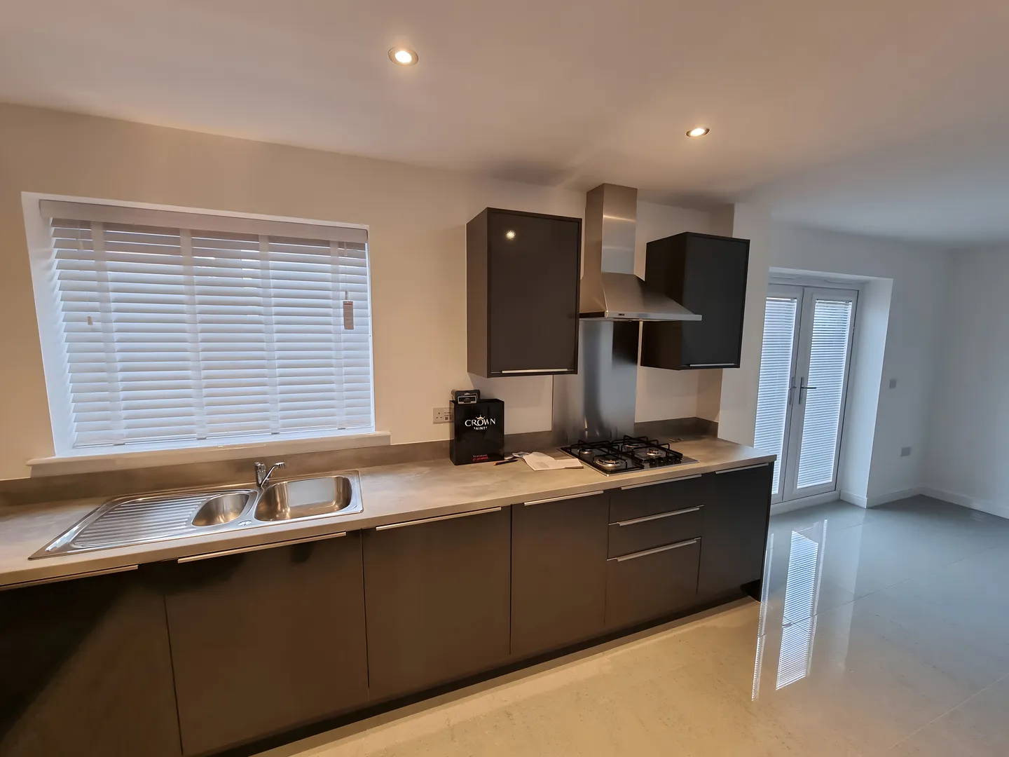 White Venetian blinds above the worktop of a grey handleless kitchen