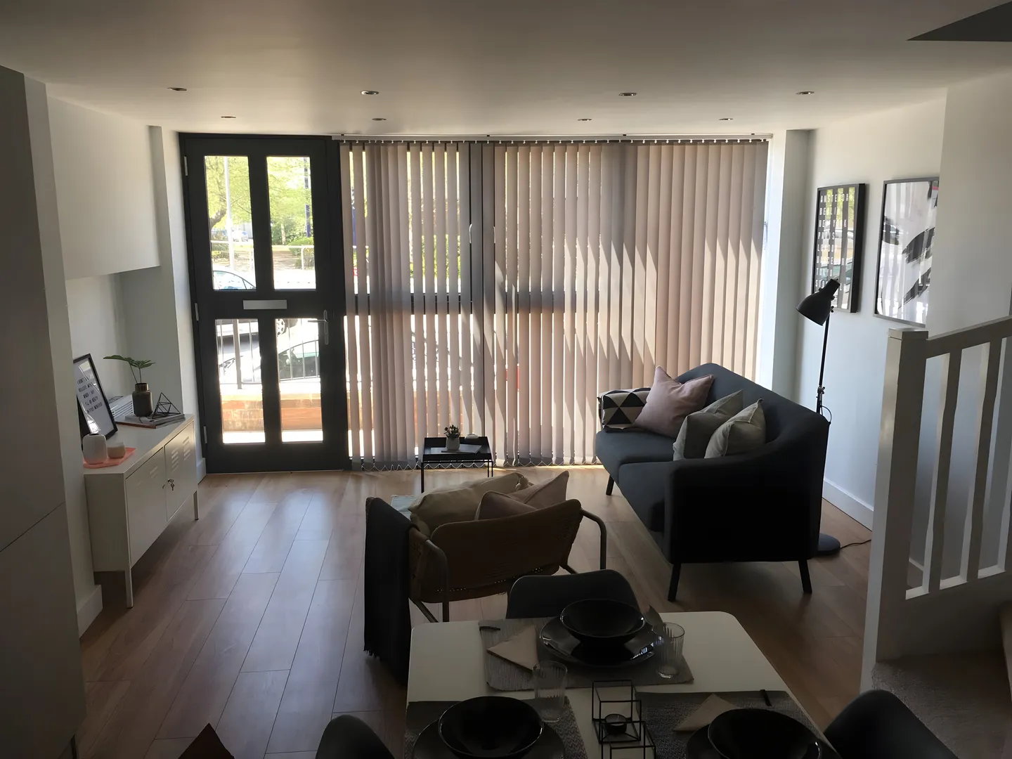 Vertical blinds fitted to the windows and doors of a living room with two sofas