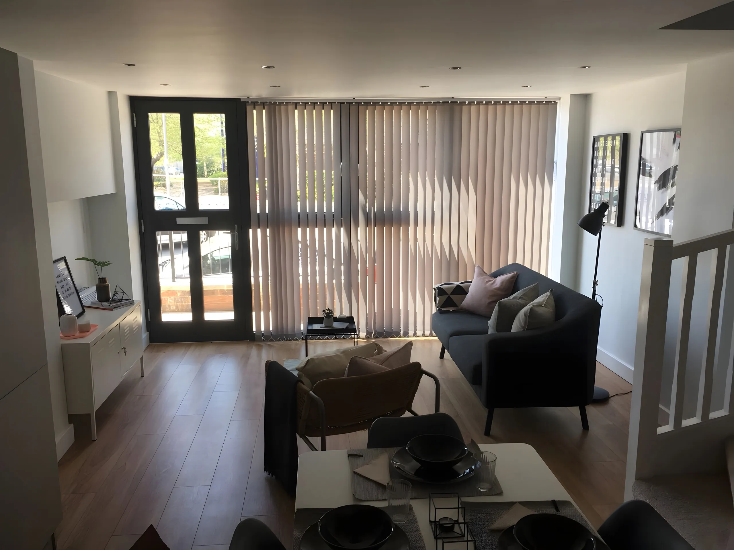 Vertical blinds fitted to the windows and doors of a living room with two sofas