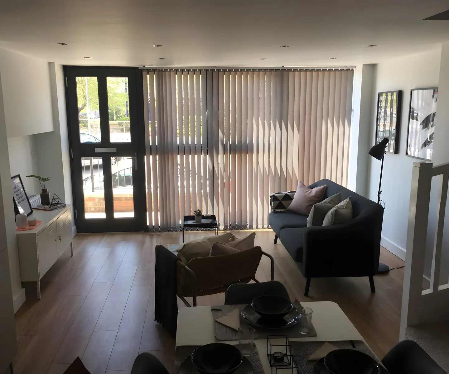 Vertical blinds fitted to the windows and doors of a living room with two sofas
